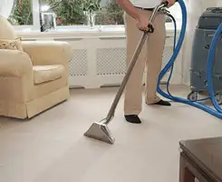 Carpet cleaning professional removing dirt and stains with a hot-water extraction tool in a home, Raleigh, NC.